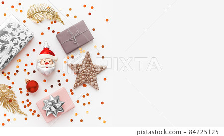 Christmas and New Year background with decorations. Santa Claus, golden feathers, silver presents and stars confetti. Copy space. 84225125