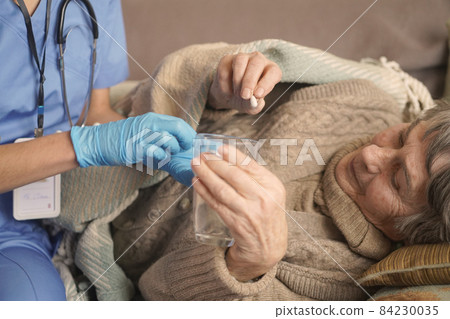 A young nurse is caring for an elderly 80-year-old woman at home. A young nurse is caring for an elderly 80-year-old woman at home. 84230035