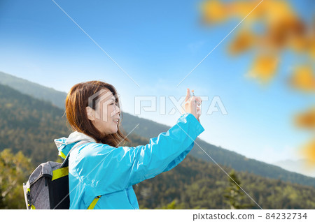 A middle-aged Japanese woman who enjoys taking selfies by climbing and trekking in [Autumn], which is easy to use as a banner. 84232734