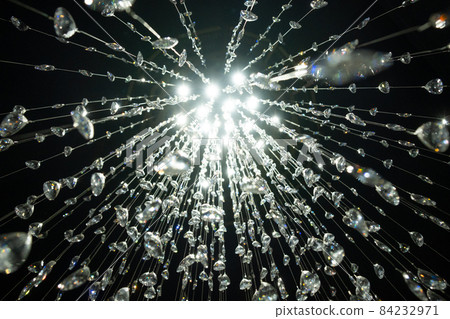 Crystal stones dangle and glisten on black background. Shining crystal chandelier. 84232971