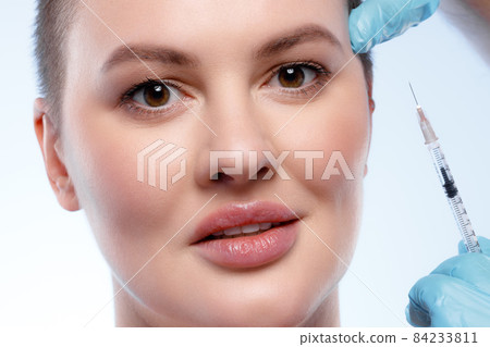 Beautiful woman with short hair gets a beauty injection in her face Beautiful woman with short hair gets a beauty injection in her face 84233811