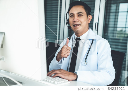 Doctor wearing headset talking actively on video call in a clinic or hospital . 84233921
