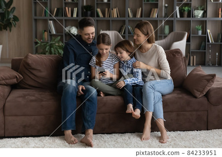 Happy family with kids using smartphone together, sitting on couch 84233951