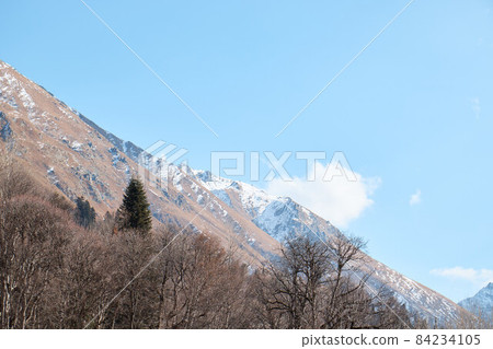 Landscape in the mountains, river and coniferous forest, autumn, the first snow on the slopes, fallen trees and shrubs 84234105
