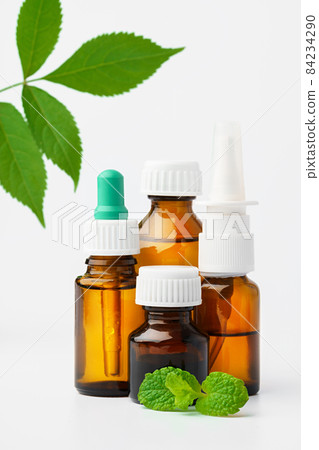 Essential oil in a small bottle with green leaf on white background 84234290