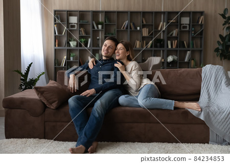 Happy Caucasian couple hugging, relaxing on couch, dreaming together Happy Caucasian couple hugging, relaxing on couch, dreaming together 84234853