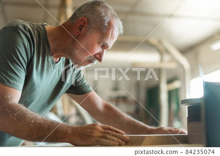 Senior man polishing the edge of a wooden step Senior man polishing the edge of a wooden step 84235074