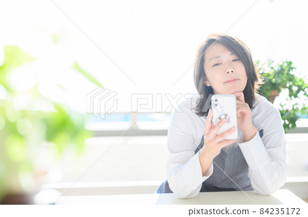Thinking with a smartphone in a bright room Japanese housewives (female) in their 30s and 40s have copy space 84235172