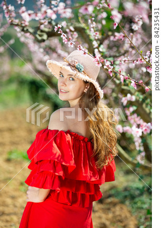 Young girl standing in spring blooming garden Young girl standing in spring blooming garden 84235431