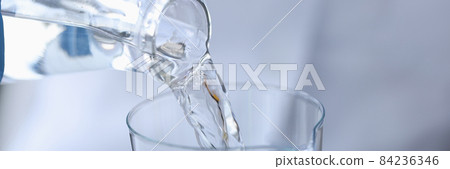 Scientist chemist pouring water from transparent bottle into flask in laboratory closeup Scientist chemist pouring water from transparent bottle into flask in laboratory closeup 84236346
