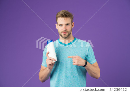 Beauty advice. Man stylish hairstyle holds hair conditioner 84236412