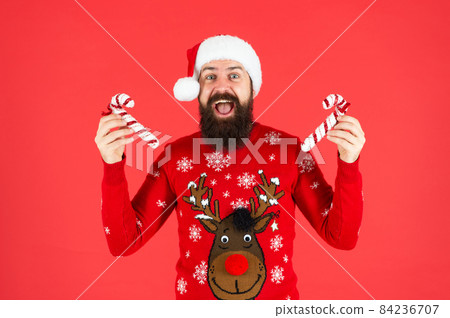 brutal hipster in winter knitted xmas sweater. mature guy with holiday candy stick brutal hipster in winter knitted xmas sweater. mature guy with holiday candy stick 84236707