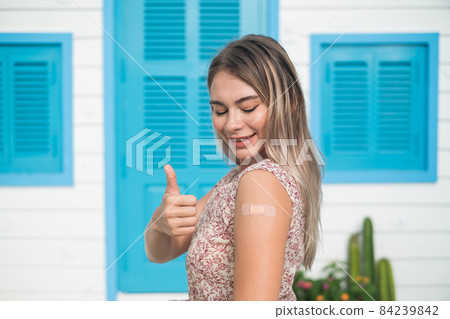 Vaccinated caucasian young woman with blond hair showing thumb up and. Covid-19 vaccine. Vaccination, immunization, disease prevention concept. Vaccinated caucasian young woman with blond hair showing thumb up and. Covid-19 vaccine. Vaccination, immunization, disease prevention concept. 84239842