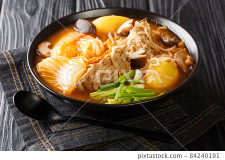 Tasty spicy Gamjatang Korean Pork Bone Soup with creamy potatoes and tender juicy pork bone meat close up in the bowl. Horizontal 84240191