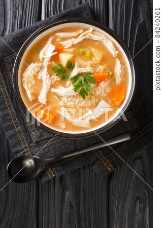 Canja de galinha is a popular chicken soup of Portuguese, Cape Verdean, and Brazilian cuisine close up in the plate. Vertical top view 84240201