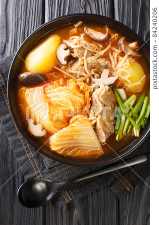 Gamjatang is soup made with pork neck bones and vegetables close up in the plate. Vertical top view 84240206