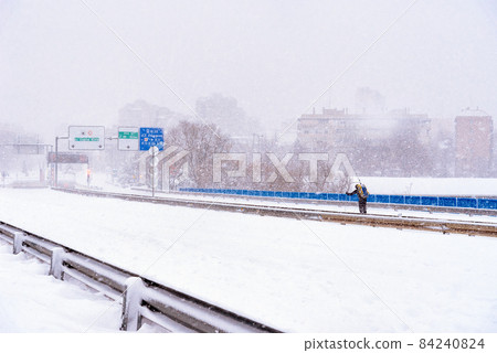 View of a highway in the city covered in snow during heavy snowfall View of a highway in the city covered in snow during heavy snowfall 84240824
