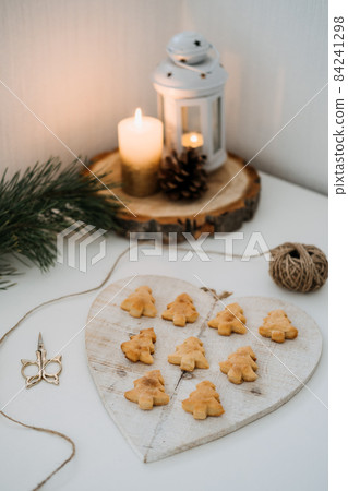 Cozy Christmas mood. Craft homemade cookies Christmas tree shape in wooden tray on table with fir tree branch and candles 84241298