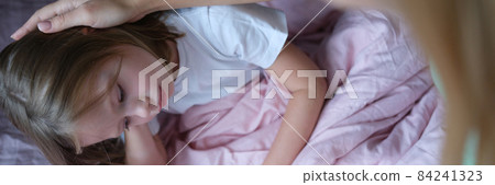 Mother stroking head of little sad girl lying in bed Mother stroking head of little sad girl lying in bed 84241323