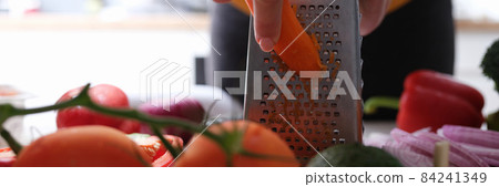 Chef grating carrots to make vegetable salad closeup 84241349