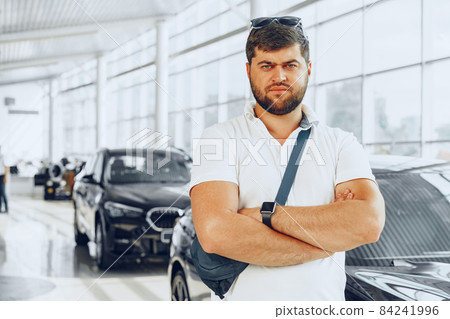 Serious young man on blurred car salon background Serious young man on blurred car salon background 84241996