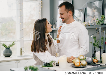 Young loving couple having good time at Christmas morning in kitchen 84242001