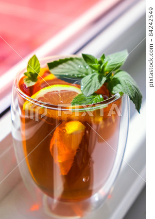 Black and green tea with lemon, cinnamon sticks and mint leaves. Hot drink. Healthy melissa tea natural organic aromatic drink in cup. Summer, Autumn winter warming drink. 84242549