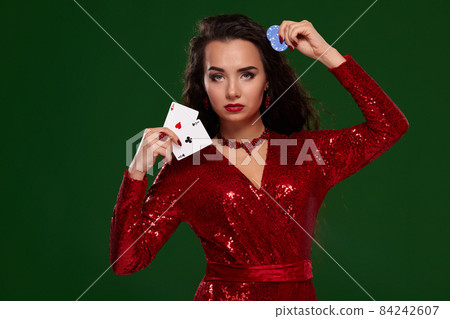 Beautiful curly woman in a glittered dress, holding some playing cards and gambling chips. Casino 84242607
