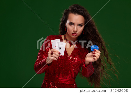 Beautiful curly woman in a glittered dress, holding some playing cards and gambling chips. Casino 84242608