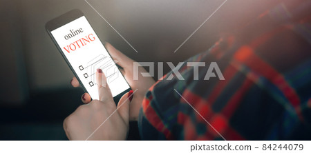 Woman votes online using the phone. Voting and elections concept. Place for text Woman votes online using the phone. Voting and elections concept. Place for text 84244079
