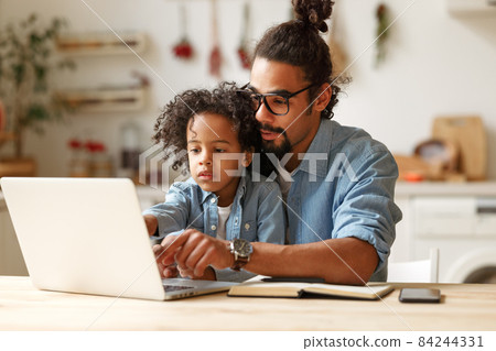 Young african american dad helping schoolboy son with homework on laptop during distant education Young african american dad helping schoolboy son with homework on laptop during distant education 84244331