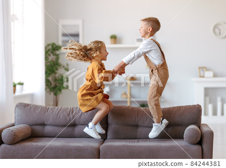 Overjoyed little children brother and sister jumping on sofa at home Overjoyed little children brother and sister jumping on sofa at home 84244381