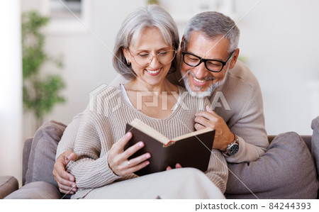 Happy smiling senior family couple in love reading book together at home 84244393