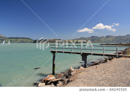 View of wooden jetty with sailing activity on weeked in Lyttelton Harbour in South Island, New Zealand View of wooden jetty with sailing activity on weeked in Lyttelton Harbour in South Island, New Zealand 84245505