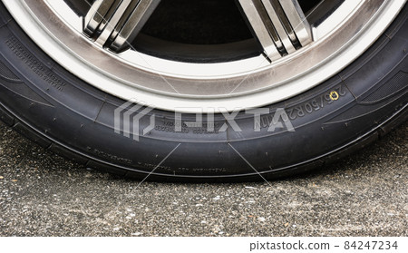 Sidewall of the car tire with a low tire pressure on the road,close up Sidewall of the car tire with a low tire pressure on the road,close up 84247234