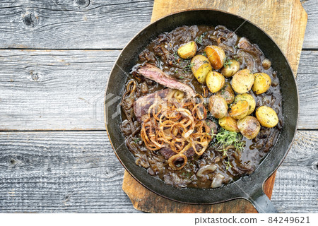 Traditional dry aged sliced roast beef with fried onion rings and potato chips Traditional dry aged sliced roast beef with fried onion rings and potato chips 84249621