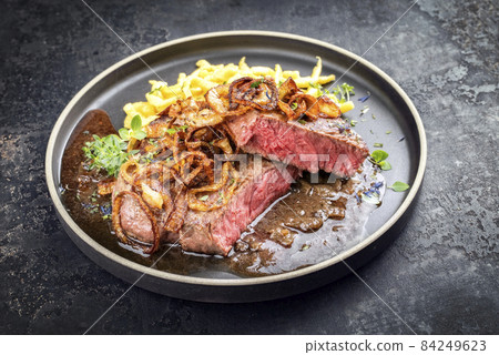 dry aged sliced roast beef with fried onion rings and Swabian spaetzle 84249623