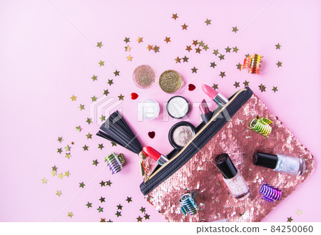 Bright composition of fashion accessories. Glitter sequins cosmetic bag with lipsticks, nail polishes and other objects. Object on soft pastel background with decorative tinsel. Flat lay, top view. Bright composition of fashion accessories. Glitter sequins cosmetic bag with lipsticks, nail polishes and other objects. Object on soft pastel background with decorative tinsel. Flat lay, top view. 84250060