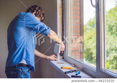 Man in a blue shirt does window installation Man in a blue shirt does window installation 84251010