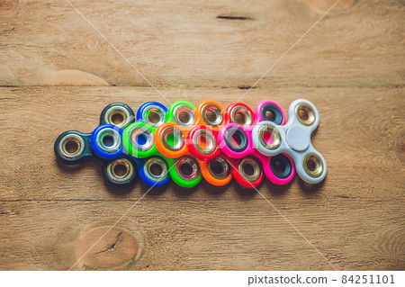 Colored fidget spinners stress relieving toy on wooden background Colored fidget spinners stress relieving toy on wooden background 84251101