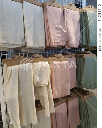 Woman fall winter or spring season scarves on eco-friendly cardboard paper hangers in clothing shop. Pastel and natural tones, neutral colors. Selective focus 84251540