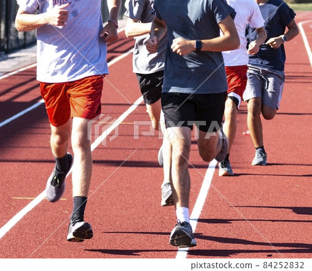 Close up of a group of boys running on a red track 84252832