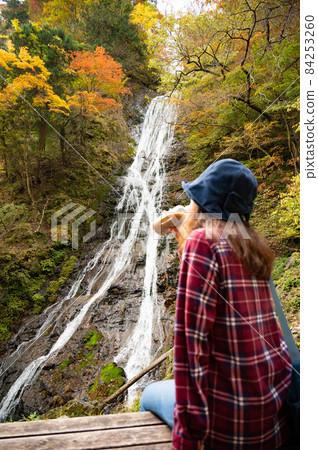 A middle-aged woman taking a break watching the autumn leaves waterfall 84253260