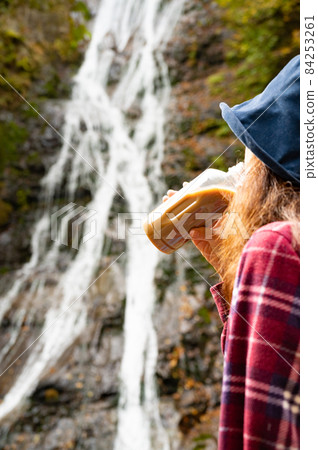 A middle-aged woman taking a break watching the autumn leaves waterfall 84253261