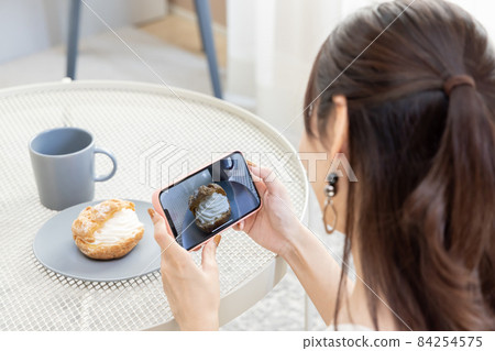 Woman taking a picture of sweets Woman taking a picture of sweets 84254575