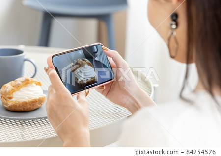 Woman taking a picture of sweets Woman taking a picture of sweets 84254576