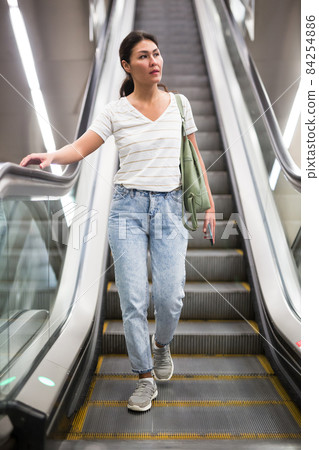 Woman going down to subway station on escalator Woman going down to subway station on escalator 84254886