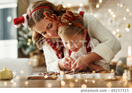 Happy family mother and son in aprons making Christmas cookies together at home Happy family mother and son in aprons making Christmas cookies together at home 84257315
