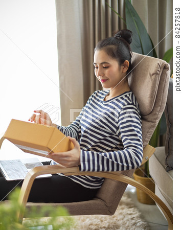 Woman receiving her package from an online shopping store Woman receiving her package from an online shopping store 84257818