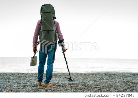 Man with metal detector searching for lost treasures on the beach 84257845